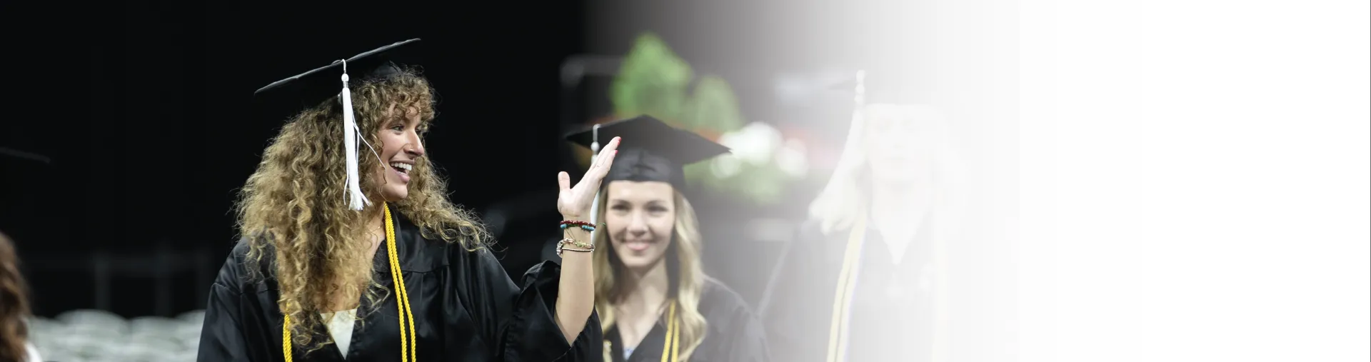 Graduate waving during commencement ceremony.